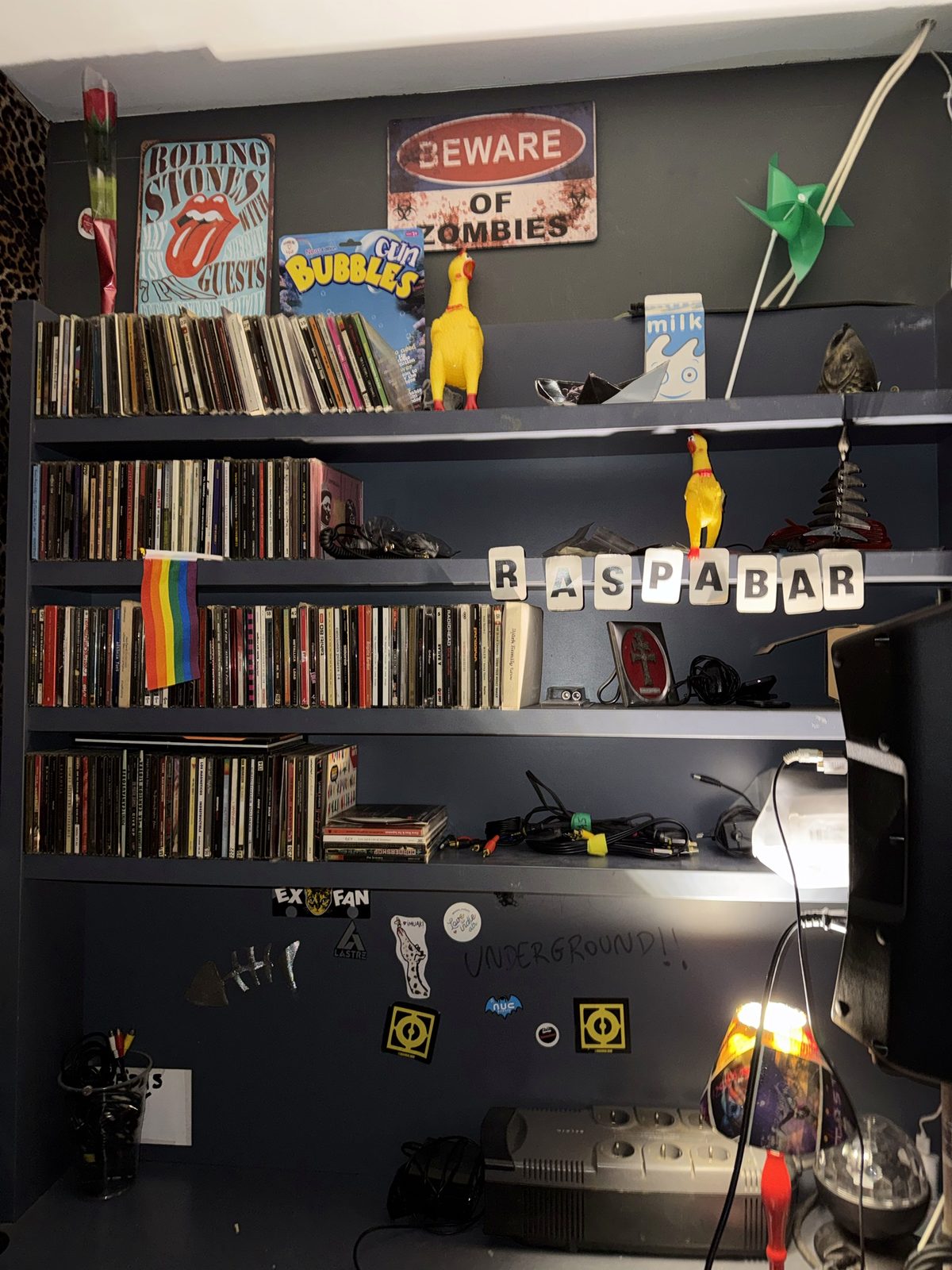 Estantería de la cabina llena de CDs, con carteles de los Rolling Stones y pegatinas