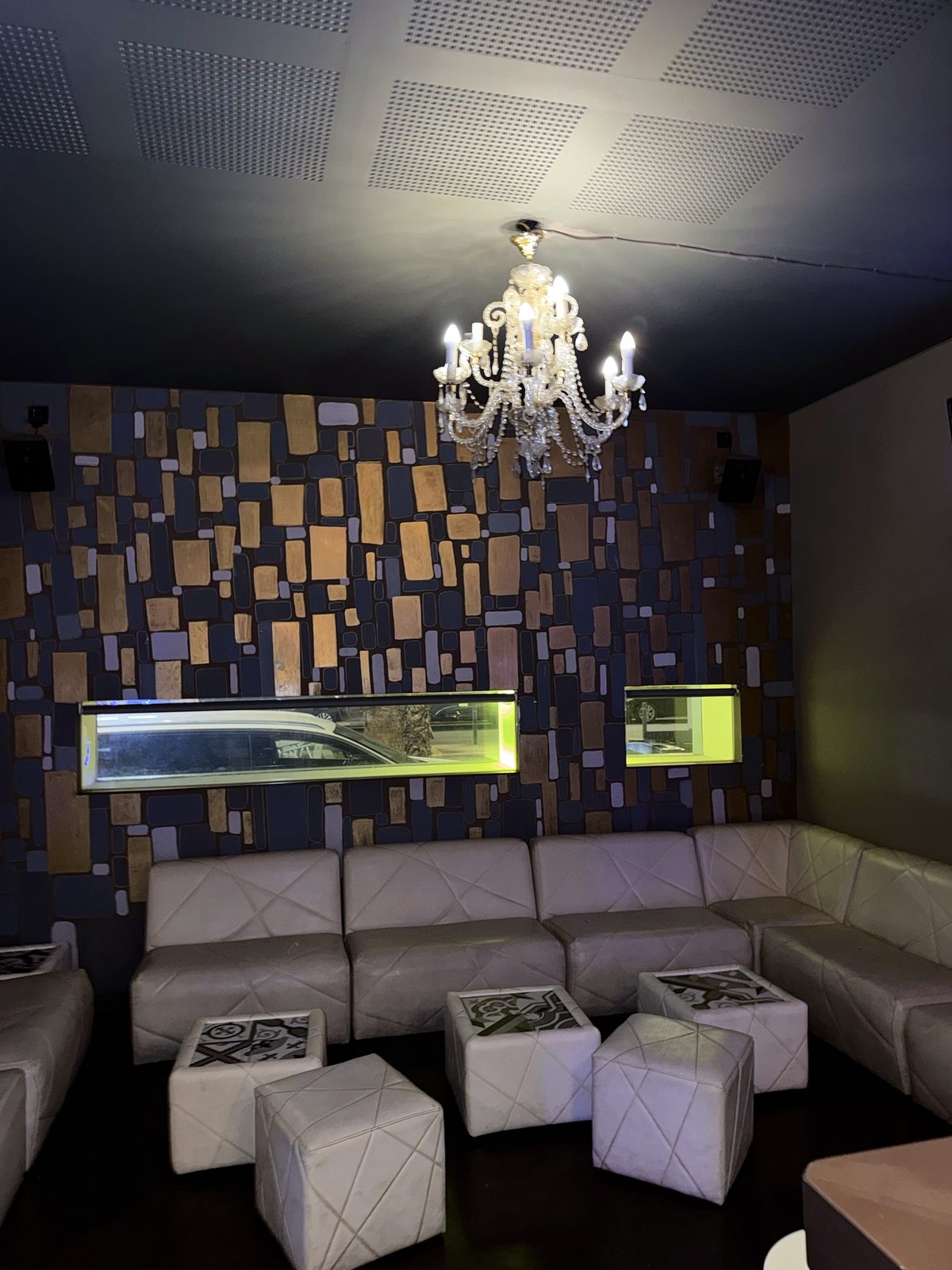 Zona de sofás blancos con lámpara de araña y pared de mosaico